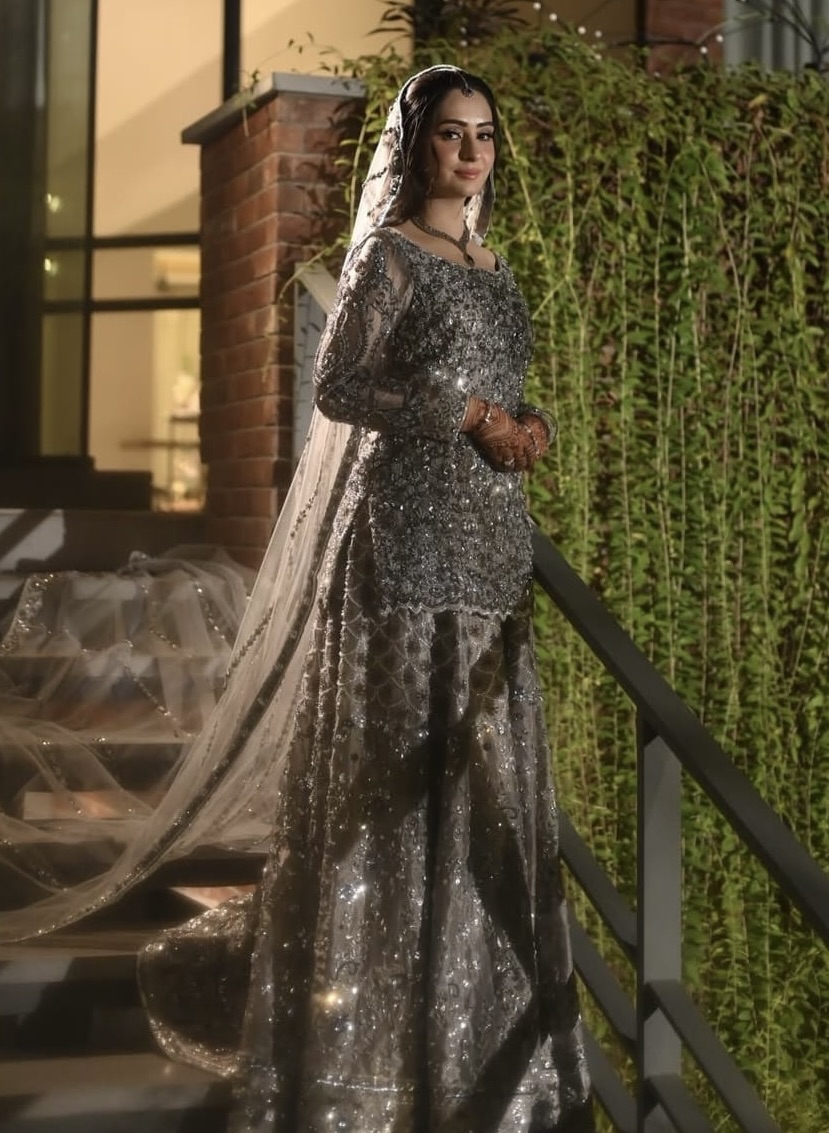 Bride in silver shimmer bridal lehenga amidst pink and white florals