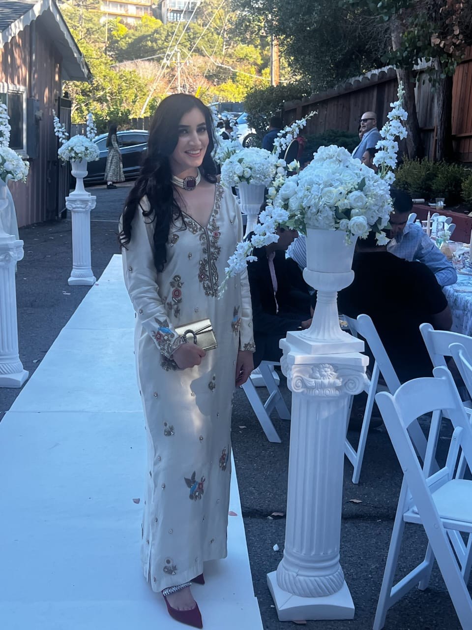 Real client in cream embroidered formal at an outdoor international reception